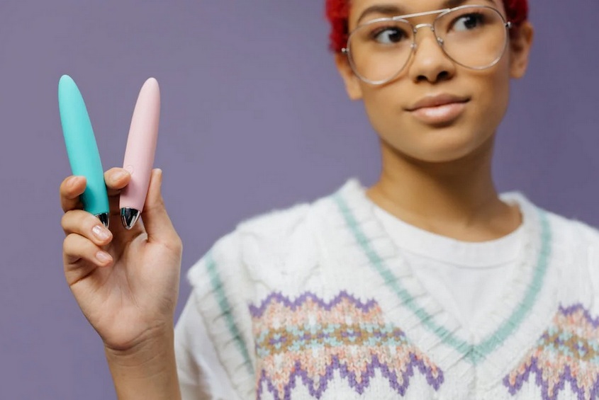 a woman in knitted sweater vest holding a vibrators